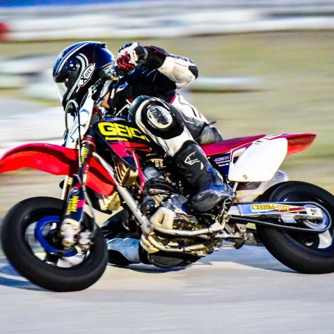 Biker riding red and black pit bike in race track
