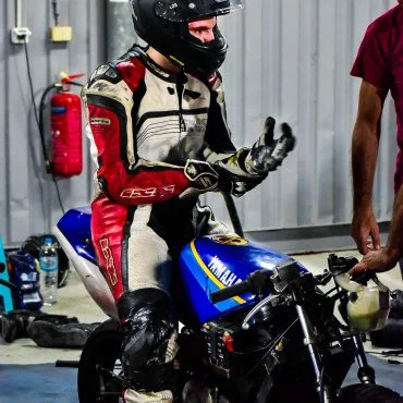 Man sitting on the motorcycle and puting his gloves