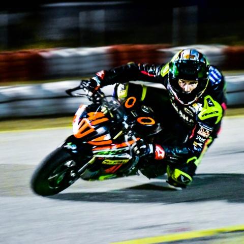 Biker riding orange and black sports bike in race track