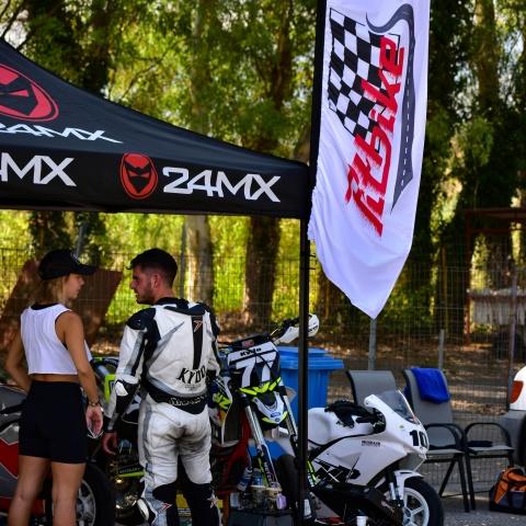 two bikers talking while standing in front of pit bikes.