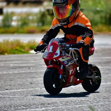 kid biker riding small sports bike in race track
