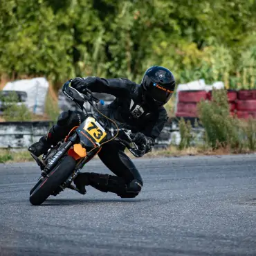 biker riding black and orange pitbike in race track