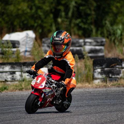 kid biker riding small red sports bike in race track
