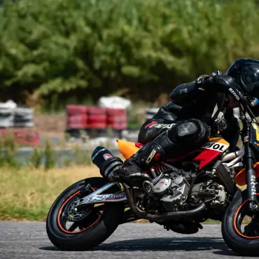 biker riding red and orange pitbike in race track