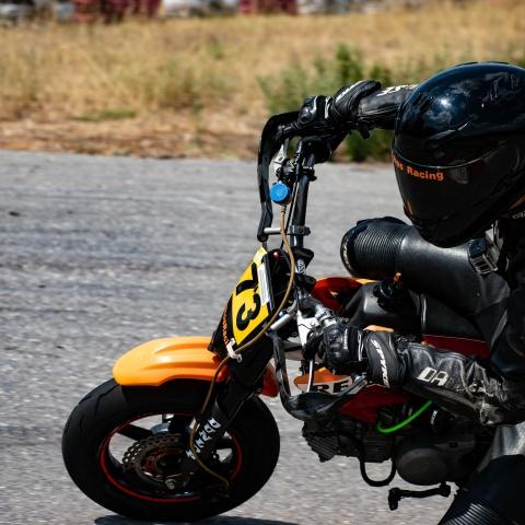 biker riding orange and red pitbike in race track
