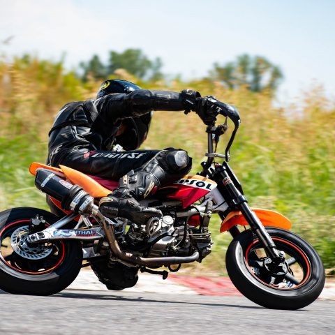 Biker riding orange and red pitbike in race track