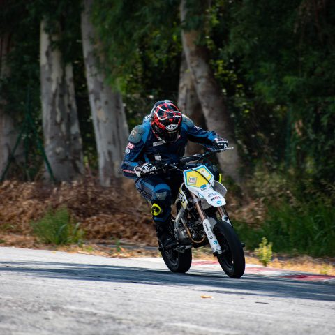Biker with helmet and body suit riding motorbike in race track