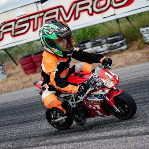 Kid biker riding small sports bike in race track