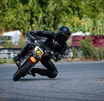 biker riding black and orange pitbike in race track