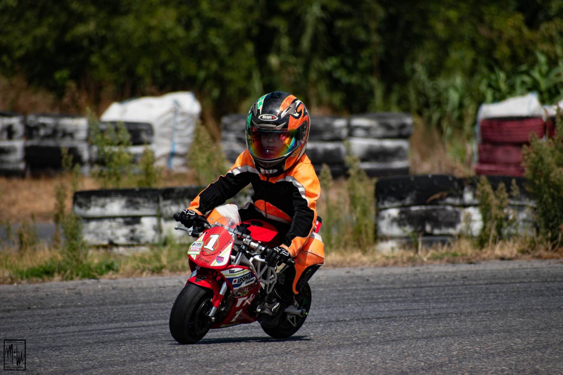 kid biker riding small red sports bike in race track